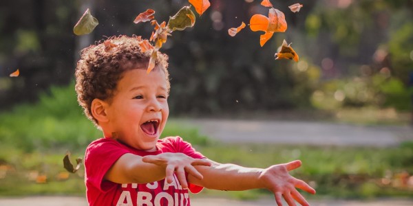 Child playing outdoors in leaves